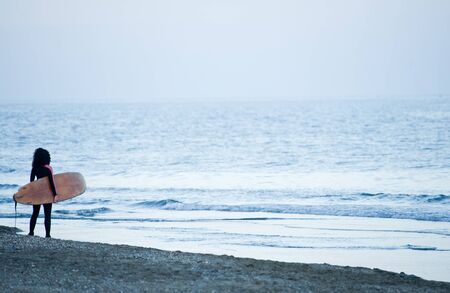girl with surfboard on the beach at sunsetの写真素材