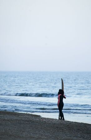 girl with surfboard on the beach at sunsetの写真素材
