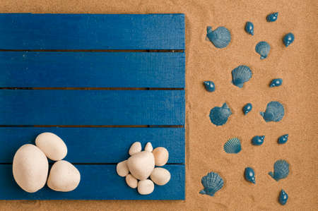 summer in the beach concept, blue wooden platform on beach sand, with white stones. beach sand with blue shells.top view. space for textの写真素材
