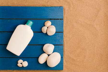 summer in the beach concept, blue wooden platform on beach sand, with white cream jar, white stones. beach sand.top view. space for textの写真素材