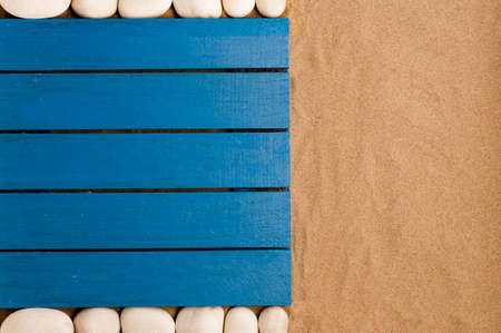 summer in the beach concept, blue wooden flooring on beach sand, white stones. beach sand background.top view. space for textの写真素材