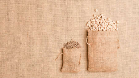 Texture or background of brown sackcloth with linen bags with lentils and chick peas. Top view