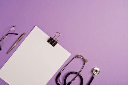 Medicine accessory, stethoscope with notepad, glasses and pen, lilac background, with copy space. top viewの写真素材