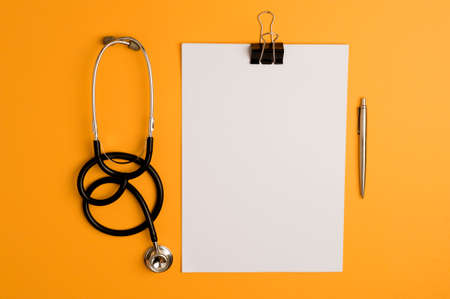 Covid-19 Coronavirus concept. medicine accessories, stethoscope, notepad and pen, orange background with copy space. top viewの写真素材