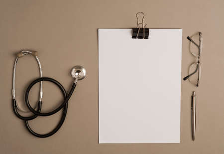 stethoscope with white notepad, glasses and silver pen, brown background, top view, text spaceの写真素材