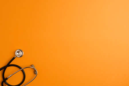 Covid-19 Coronavirus concept. Stethoscope medicine accessory, orange background with copy space. top viewの写真素材