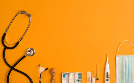 covid-19 concept (coronavirus) with medical instruments and protection material, orange background,...