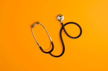 Covid-19 Coronavirus concept. Stethoscope medicine accessory, orange background with copy space. top viewの写真素材