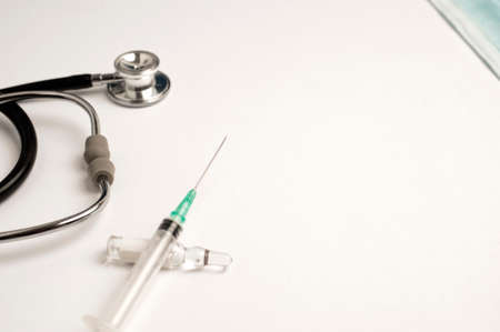 coronavirus (covid-19) vaccine concept syringe with glass container, stethoscope, white background, top viewの写真素材
