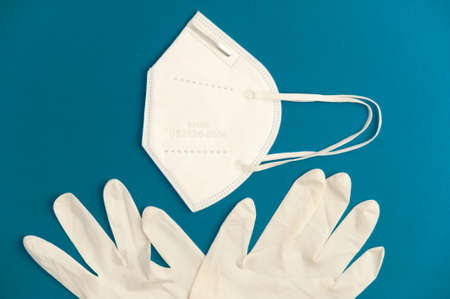 Covid-19 concept, white nk95 mask with virus protection hygienic gloves, turquoise background. Top viewの写真素材