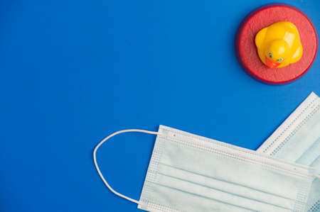 underage education concept covid-19, virus protection surgical masks with yellow duck with red protection zone, blue background, space for text. top viewの写真素材