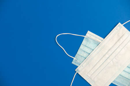 covid-19 concept, partial view of virus protection surgical masks with blue background, space for text. top viewの写真素材