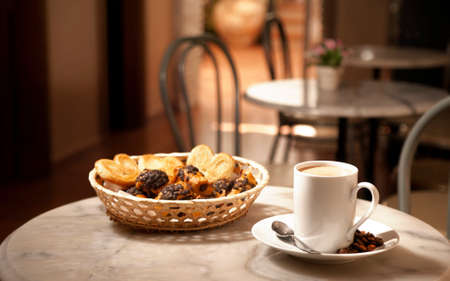 cup of coffee, on marble table, with pastries in wicker basket, cafeteria tables backgroundの写真素材