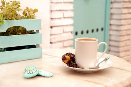 cup of coffee with sweet on marble table, with painted stones and box with plants, mediterranean house backgroundの写真素材