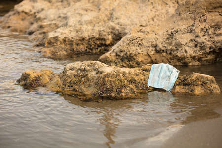 Discarded to single-use virus face masks. Environmental pollution, with autumn leaves and plastic...