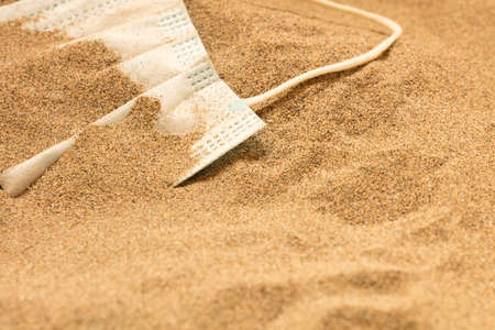 Waste during COVID-19. Scrapped to ocean coronavirus single-use face masks. Environmental and coastal plastic pollution. Trash on the beach that threatens the health of the oceans.の写真素材
