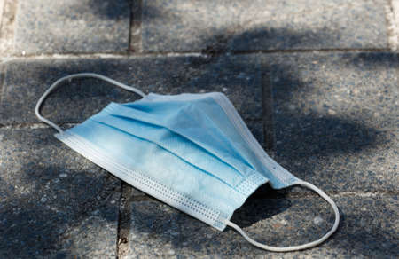 Medical protection mask lost on the ground was used. Disposable mask lying on the street....