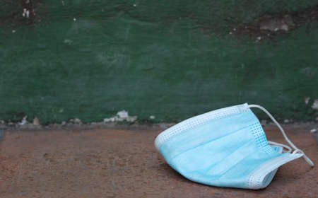 Medical protection mask lost on the ground was used. Disposable mask lying on the street. Incorrectly discarding the used face maskの写真素材