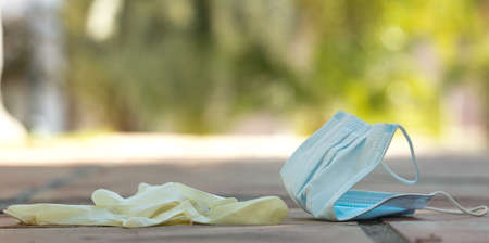 A medical protective mask and surgical gloves were used, lost on the ground. Disposable mask lying...