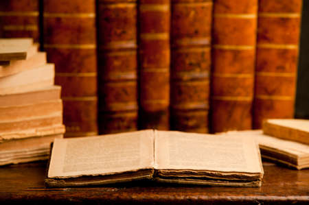 open old book with stack of old retro books on old wooden table and dark backgroundの写真素材