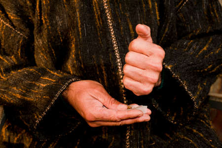 man hands with dark green djellaba, cigar in hand, prepares hashish cigar with white smoking paper, hashish cigar preparationの写真素材