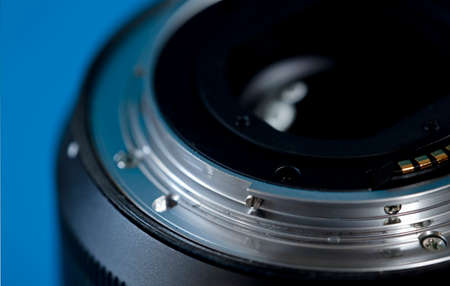 Photographic lens, photographic bayonet, camera on blue background (selective focus on metal ring).