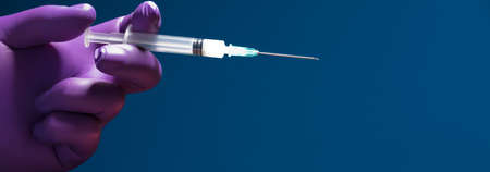 syringe in doctor's hand, blue backgroundの写真素材