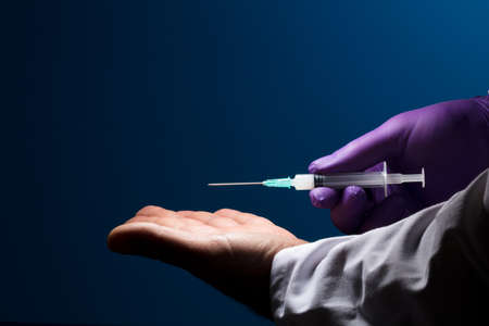 doctor offers vaccine with kind gesture, syringe and purple glove