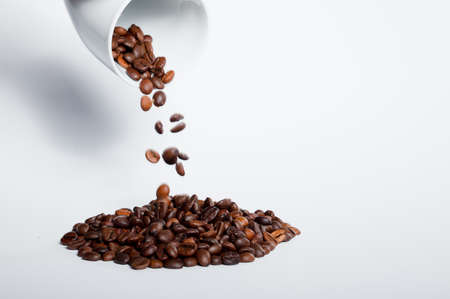 Isolated coffee beans (selective focus on coffee beans) with ceramic cup, white background.の写真素材