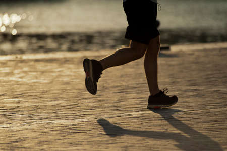 runner training at sunset black shorts and black sneakers sea bottomの写真素材
