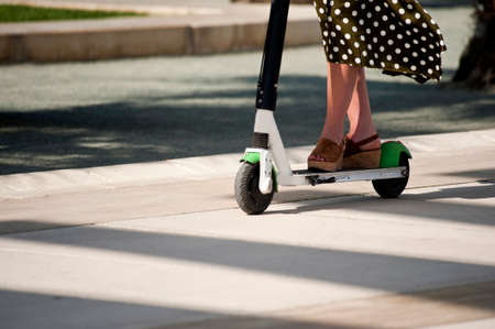 woman on electric scooter with dress flying in the windの写真素材