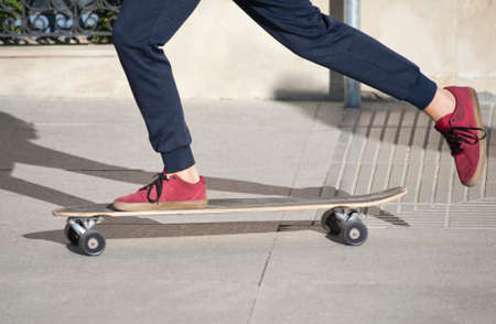 boy skating on street smooth floor blue pants and red shoes