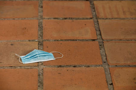 Medical protection mask lost on the ground was used. Disposable mask lying on the street. Incorrectly discarding the used face maskの写真素材