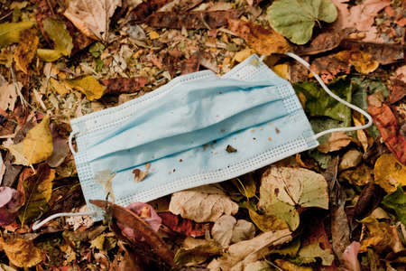 Waste during COVID-19. Discarded to single-use coronavirus masks. Environmental pollution, on dry leavesの写真素材