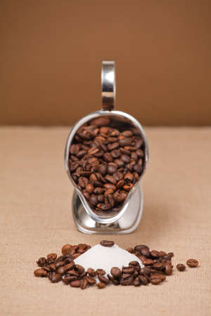 coffee bean on pile of sugar, silver container with coffee and brown backgroundの写真素材