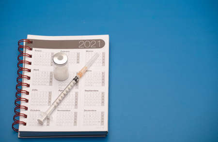 syringe and vaccine canister, with calendar 2021, blue backgroundの写真素材