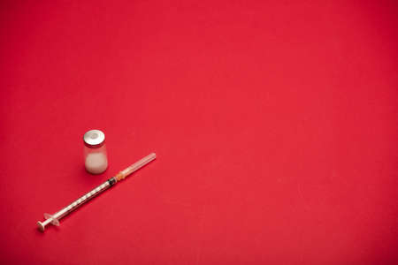 syringe with vaccine bottle, red backgroundの写真素材