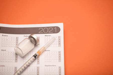 calendar 2021 with syringe and vaccine canister, orange backgroundの写真素材