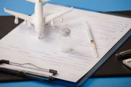 Vaccine with syringe, flight data form, and white plane, blue background