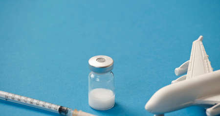 vaccine canister with syringe and white plane, blue backgroundの写真素材