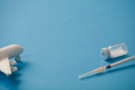 vaccine canister with syringe and white plane, blue background