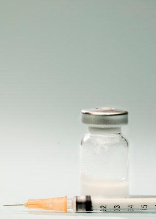 syringe with orange cannula, vaccine in glass vial, on blue backgroundの写真素材