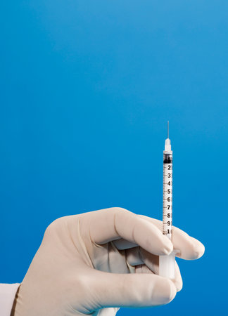 syringe in the hands of doctor with gloves and blue backgroundの写真素材