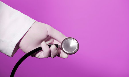 Stethoscope in doctor's hands with surgical gloves lilac backgroundの写真素材