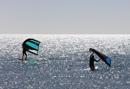 men practicing with wing-surfer at sunset in the seaの写真素材