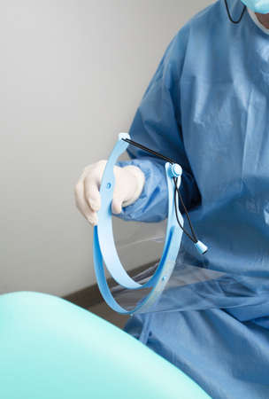 dentist with face shield in hands, with patient chair, detailed planの写真素材