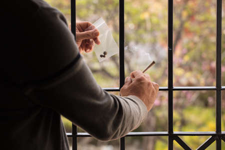 drug dealer in jail, hands with hashish joint with transparent plastic bag and cannabis inside.Drug trafficking in jail Drug consumption and sale conceptの写真素材