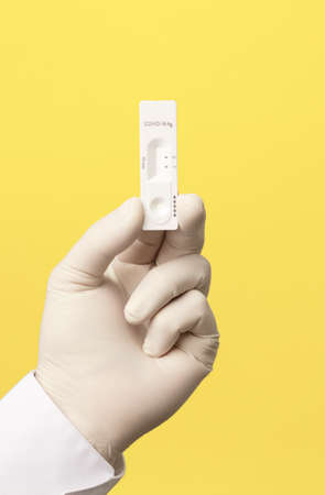 COVID-19 virus disease test in doctor hands, coronavirus crisis test, global pandemic outbreak, deadly SARS-CoV-2 epidemic, test kit illustration, yellow backgroundの写真素材
