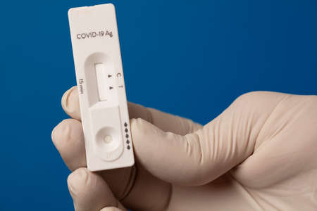 COVID-19 virus disease test in the hands of doctor, coronavirus crisis test, global pandemic outbreak, deadly SARS-CoV-2 epidemic, test kit illustration, green backgroundの写真素材
