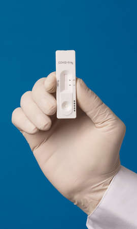 COVID-19 virus disease test in the hands of doctor, coronavirus crisis test, global pandemic outbreak, deadly SARS-CoV-2 epidemic, test kit illustration, green backgroundの写真素材